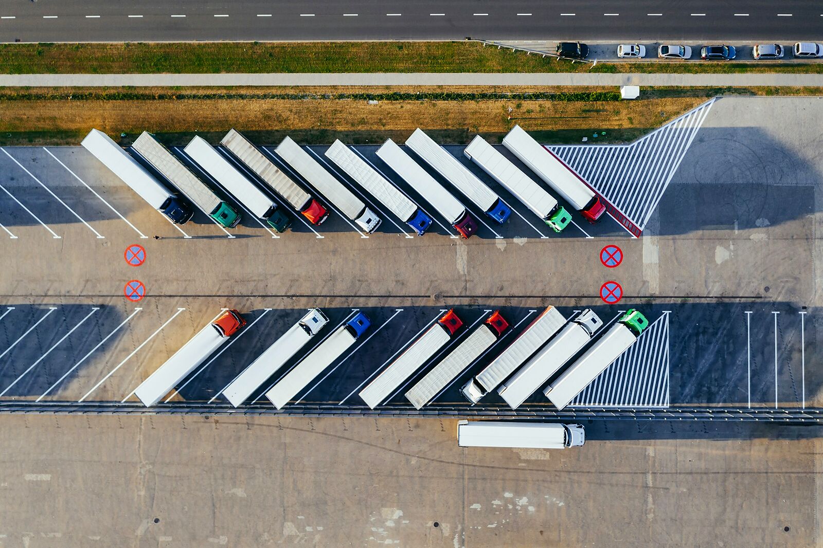 Vue aérienne d'un parking de camions semi-remorques alignés sur une aire logistique.